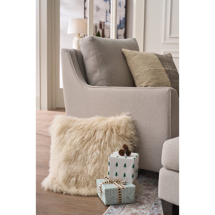 Wrapped gifts beside a cream accent chair with a shearling pillow
