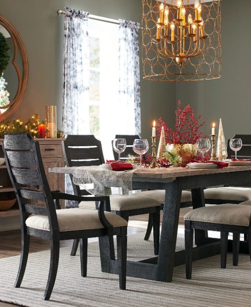 Trestle dining table set for a holiday dinner with candles and red berries