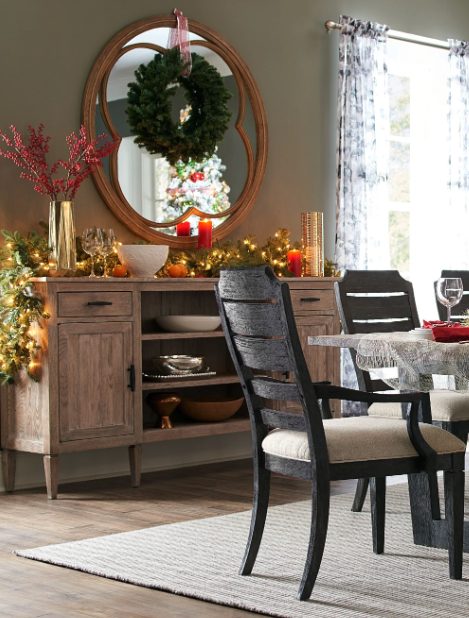 Wood sideboard with garland, red candles and a wreath reflected in a mirror